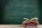 Education and reading concept - group of colorful books on the wooden table in the classroom, blackboard background