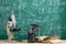 Education and sciences concept - books on the teacher desk in the auditorium, chalkboard on the background