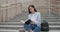 Education in university college concept - young lady making notes in notebook while sitting outdoors on steps