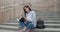 Education in university college concept - young lady making notes in notebook while sitting outdoors on steps