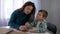 Education Visually impaired children, mom teaches blind son boy to write braille characters font sitting at table in