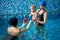 Educational games in pool with parents and specialist. Cute baby boy interested in communication with swimming trainer