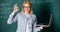 Educator smart clever lady with modern laptop searching information chalkboard background. Woman wear eyeglasses holds