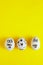 Eeaster symbol eggs in medical masks and painted coronavirus bacteria on yellow background, space for text, vertical view.