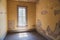 Eerie interior room in an abandoned home in Bannack Ghost Town Montana, with peeling paint, exposed walls and an old window