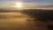 Eerie scenery of sunrise above clouds over misty mountains