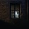 Eerie Window Watcher: Ghostly Figure Peering Out