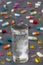 Effervescent tablet in water with bubbles with Multicolored Pills and Capsules on grey slate background