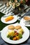 Egg Benedict slider with vegetable salad include tomato, potato, lettuce leaf and carrot with tea, coffee, and sweet melon served