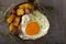 Egg with fries and fried salami in a rustic pan