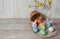 An egg hunter`s basket that fell on its side, colorful eggs on a wooden background.