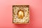 Egg made of gold in a wooden box on a pink background. The concept of exclusivity and superprize. Minimalistic composition