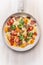 Egg omelette in white frypan with tomatoes,bread, cheese and sausage on white wooden background, top view