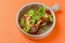 Egg-plant rolls with meat and pomegranate seeds served in a bowl over orange background