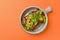 Egg-plant rolls with meat and pomegranate seeds served in a bowl over orange background