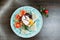 Egg `Poached ` with slices of fresh tomatoes and fried toasts with delicious pate and greens on a blue plate in a restaurant