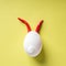 Egg shell and red hot chilli pepper imitation rabbit hare face of devil clown on yellow colored background pape