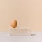 Egg on top of travertine marble block on a beige and gray background. 2021 Easter unique still life concept.