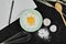 Egg yolk on flour, notebook, whisker and spoon on dark table