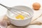 Egg yolk with flour and whisk in bowl. Eggshell and egg on table