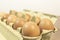 Egge, ten brown eggs in a carton package on a wooden table