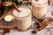 Eggnog in glass cups with a delicate foam, spices and a cinnamon stick