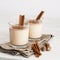 Eggnog in glass cups with a delicate foam, spices and a cinnamon stick