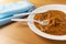 Eggplant curry meal on a white plate with plastic silverware