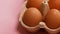 Eggs in basket. Open egg box with organic brown eggs on pink background.