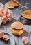 Eggs, bowl, whisk and finished burger on gray background