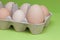 Eggs in carton, the biggest among another small eggs. on the light green background