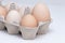 Eggs in carton, the biggest among another small eggs. on the white background