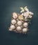 Eggs in carton box with decorative spring blossom on dark gray background, top view.