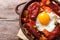 Eggs with chorizo, potatoes and tomatoes in a pot. close up top