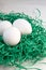 Eggs in a green paper nest. Three white eggs