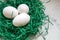 Eggs in a green paper nest. Three white eggs