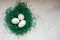 Eggs in a green paper nest. Three white eggs