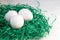 Eggs in a green paper nest. Three white eggs