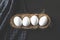 Eggs lined up in a row in a nest on black rustic background