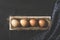 Eggs lined up in a row in wooden crate on black rustic background