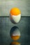 Eggshell stuck in the air above the table with an orange ball, surreal still life