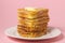 Eggy bread on a pink background. Butter melts on a stack of eggy breads.
