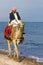 Egypt, Taba - December 25, 2012: Local male resident riding a camel on the Sinai beach of the red sea, Egypt