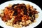 Egyptian cuisine of Koshary isolated on black background, a popular street food made of rice, macaroni, and lentils mixed together