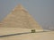 Egyptian pyramid, small figure of man and touristic bus