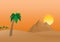 The Egyptian Pyramids of Giza at sunrise in the dune sand with orange sun in the background of palm trees with brown trunk with gr