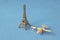 Eifel tower model with little toy plane on blue background. Famous French landmark and airplane miniatures, Paris