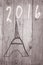 Eiffel Tower arranged from wooden sticks.Date 2016 written on grey background.