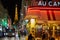 Eiffel tower illuminated at night and street with bus, people and typical restaurant in Paris, France