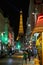 Eiffel tower illuminated at night and street with people and typical restaurant in Paris, France